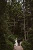 bride and groom walking in the middle of tall trees- Dolomites Elopement