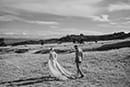 bride and groom walking in the road as the wind blows at them- Taupo Wedding