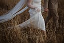 bride and groom walking in the middle of tall grass- Taupo Wedding