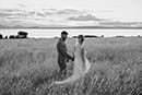 bride and groom walking in the tall grass as wind blows at them- Taupo Wedding